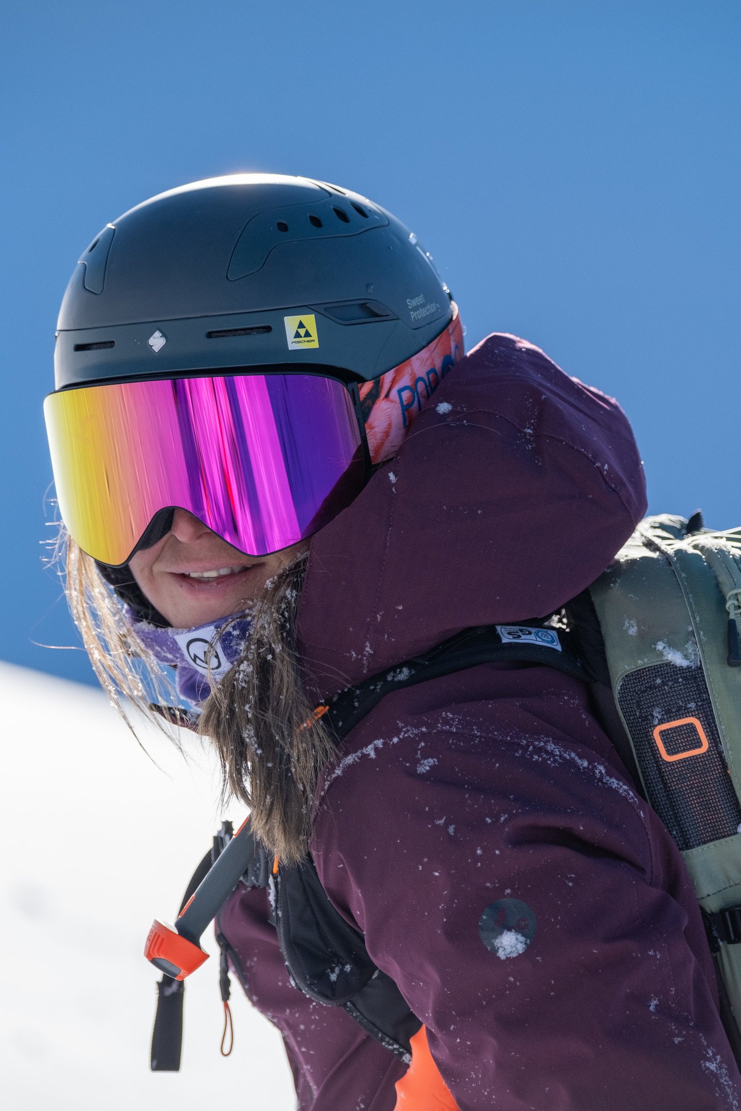 Athletin trägt LARRY Skibrille Birdie Orange, pinke Scheibe, orange-blaues Band, OTG-Funktion für Damen.