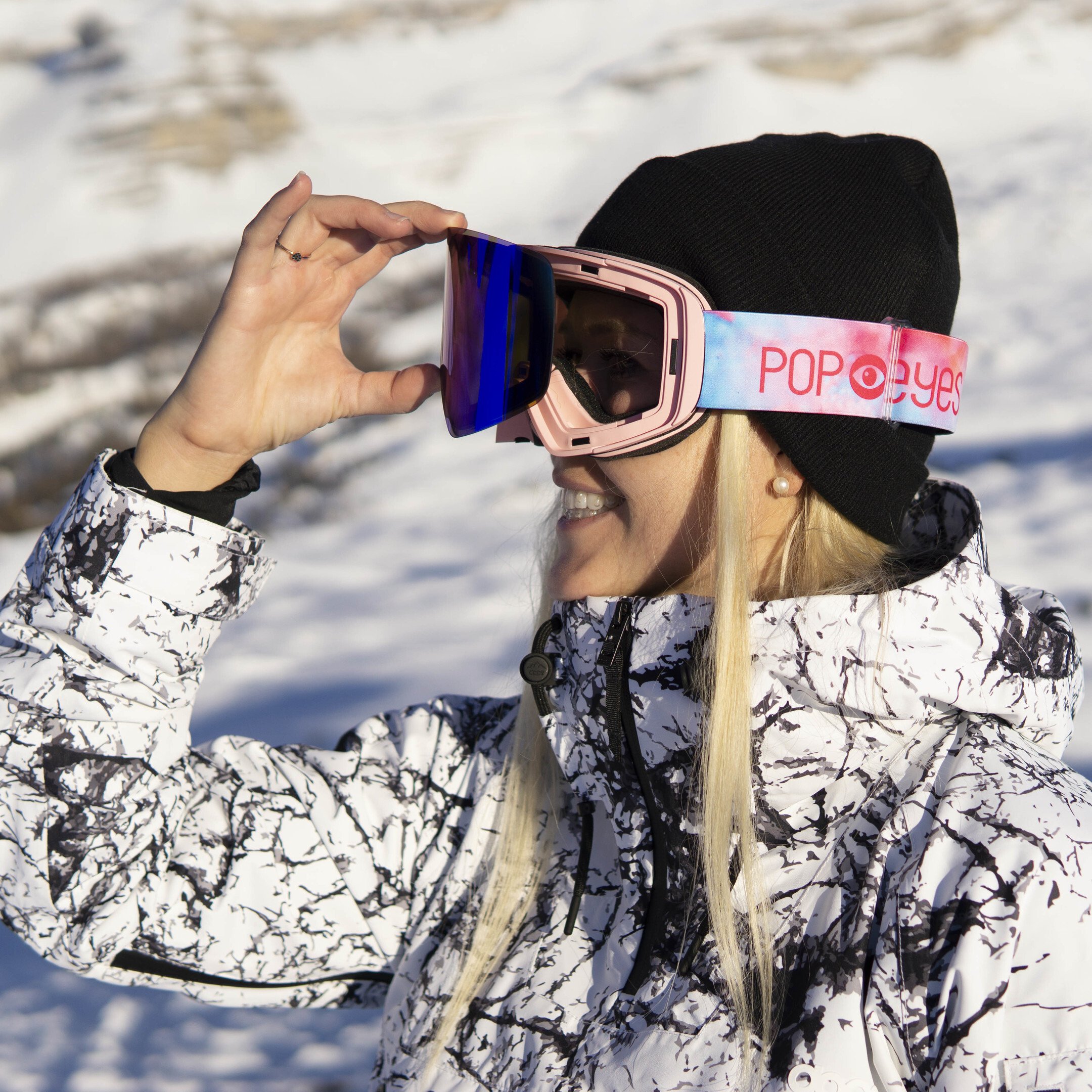 Athlete showcasing the interchangeable lens of ski goggles JAMIE Baby Pink, blue lens, pink design strap, perfect for women.